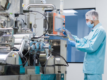 In a scientific setting, a scientist in a lab coat carefully manipulates a machine.