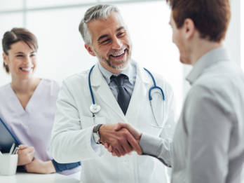 A physician shaking hands with two people to represent cooperation in the medical field.
