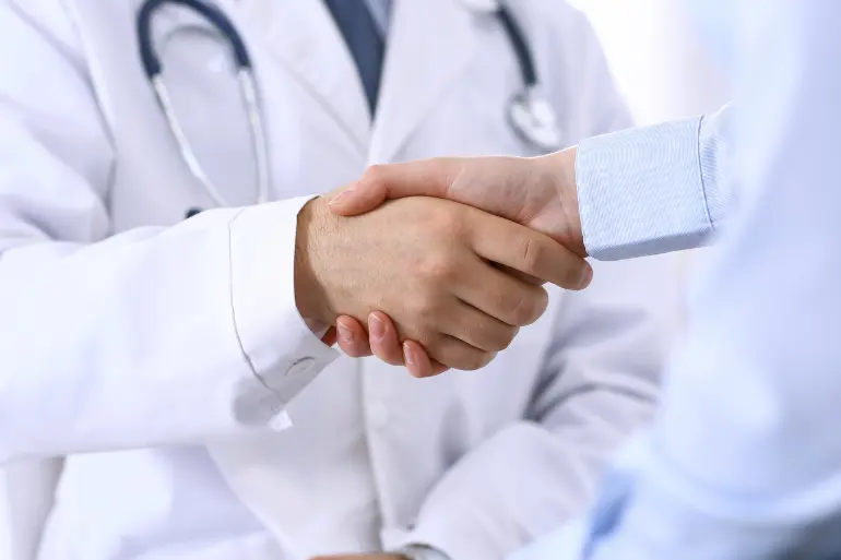 A medical professional is shaking hands with a business partner for healthcare growth opportunities