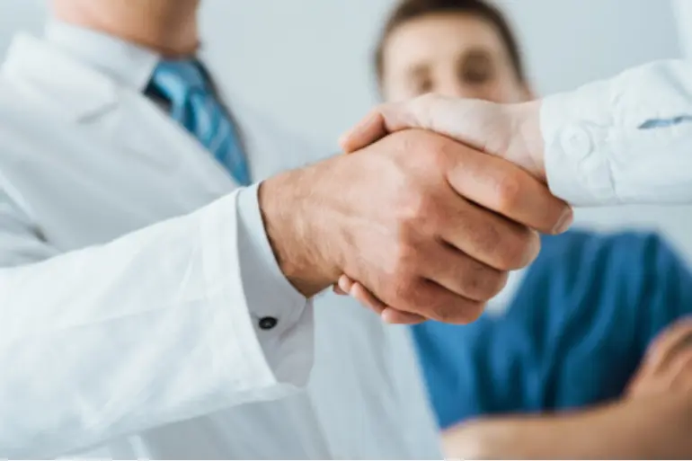 Doctors hold hands with a business expert, working together in teams in a medical environment.